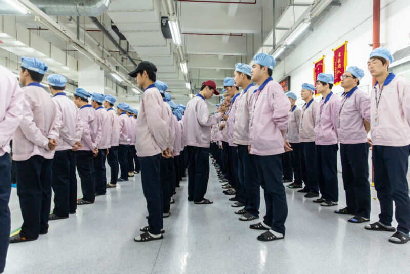 Employees line up for row call before their shift starts at a Pegatron Corp. factory in Shanghai, China, on Friday, April 15, 2016.