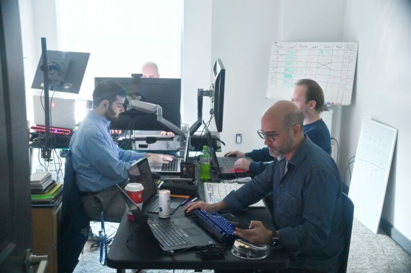 Four men sitting in front of computers in a workplace.
