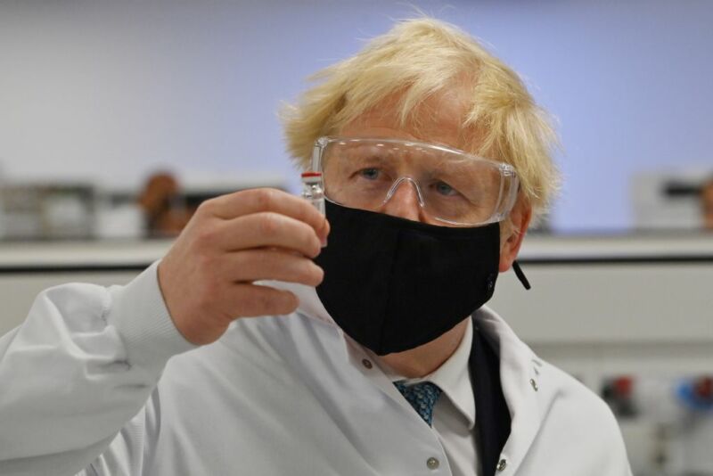 Image of a man with goggles and a face mask, holding a vial.
