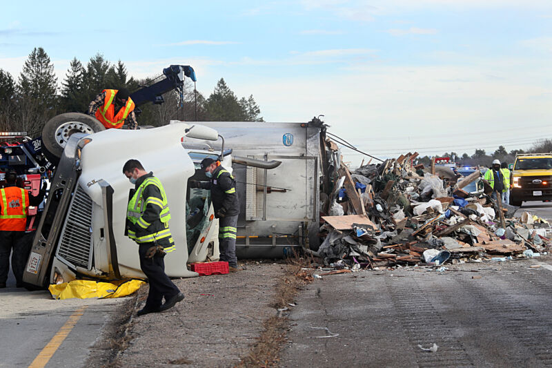 Road Workers Attend To An Overturned Semi Truck.