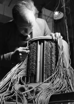 Christopher Strachey in 1955 with the Ferranti Mark 1, (also known as the Manchester Electronic Computer).