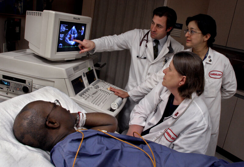 Image of a patient in bed being attended by three doctors.