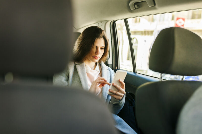 Young businesswoman sitting on the back seat of a car using a cellphone