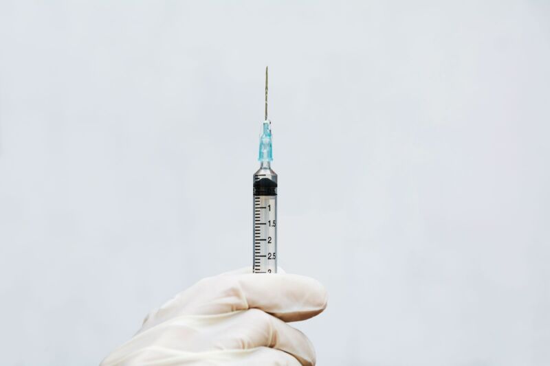 Stock photo of gloved hand with medical needle.