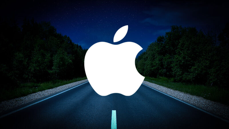 An Apple logo was photographed on a deserted road at night.