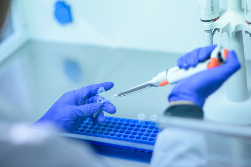 A researcher in protective equipment fills scales.