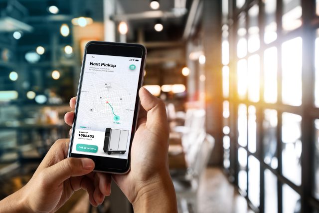 A hand holding a cellphone showing a map with a delivery route on it