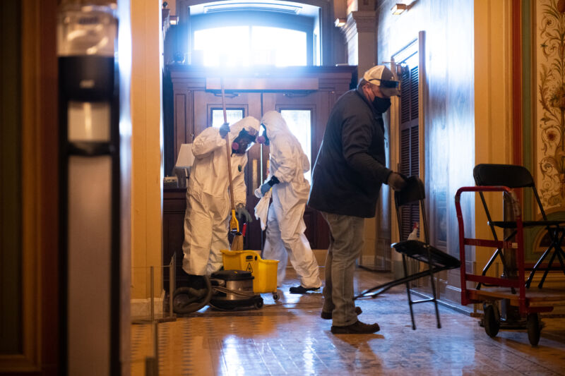 Workers wearing personal protective equipment (PPE) clean an entry to the US Capitol in Washington, DC, on Sunday, Jan. 10, 2021. 