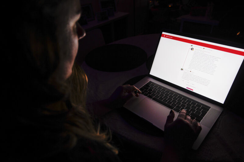 The bright screen of a notebook computer illuminates the face of the person using it.