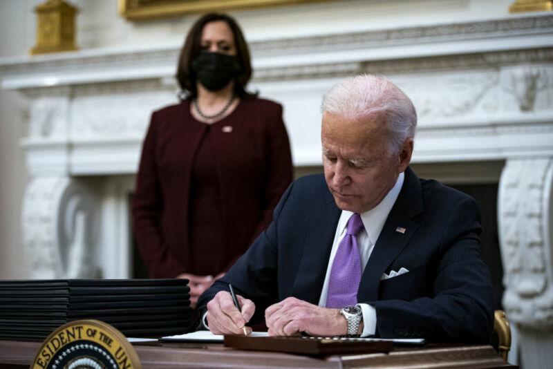 Image of a man seated at a desk with a woman standing behind him.