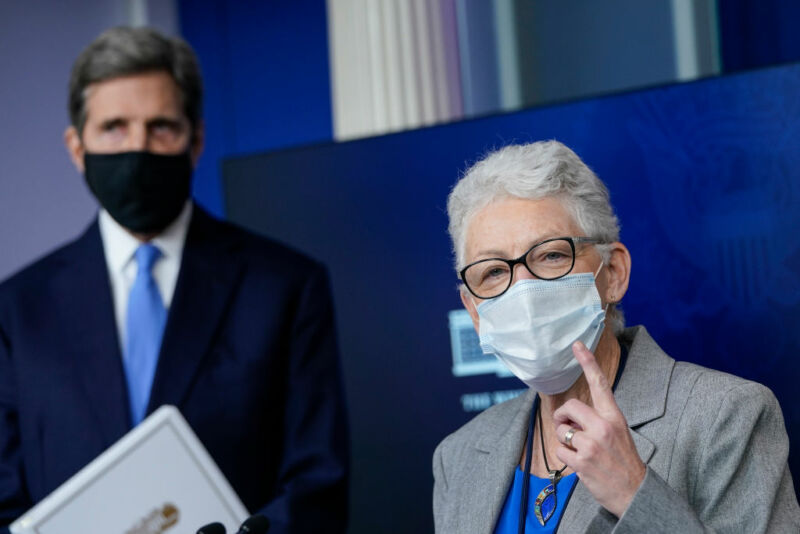 A woman speaks while a man stands behind her.