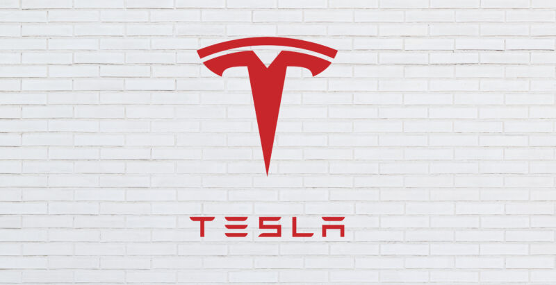 A brick wall with the Tesla logo superimposed on top