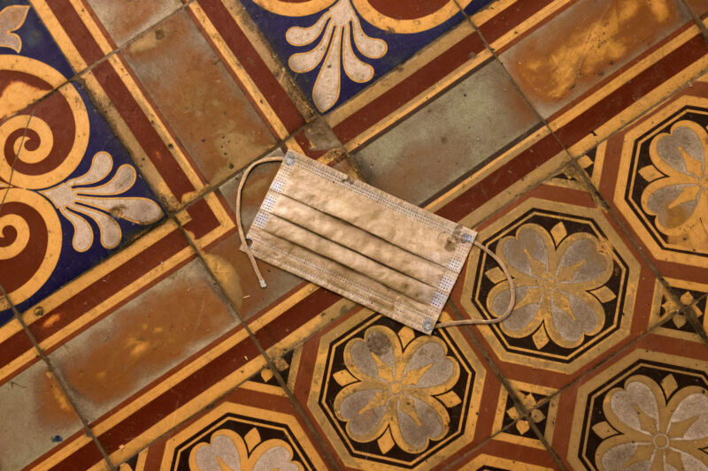 A soiled mask is discarded on a cracked tile floor.