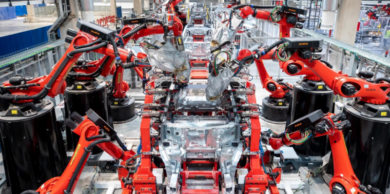 Robot arms work on an assembly line.