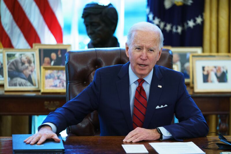 An Older Man In A Suit Speaks From The Resolute Desk.