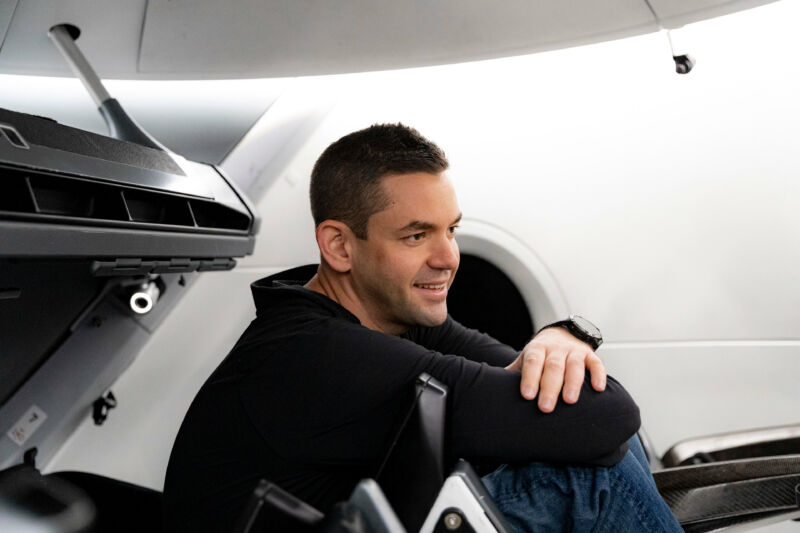 A young man smiles while sitting amidst machinery.