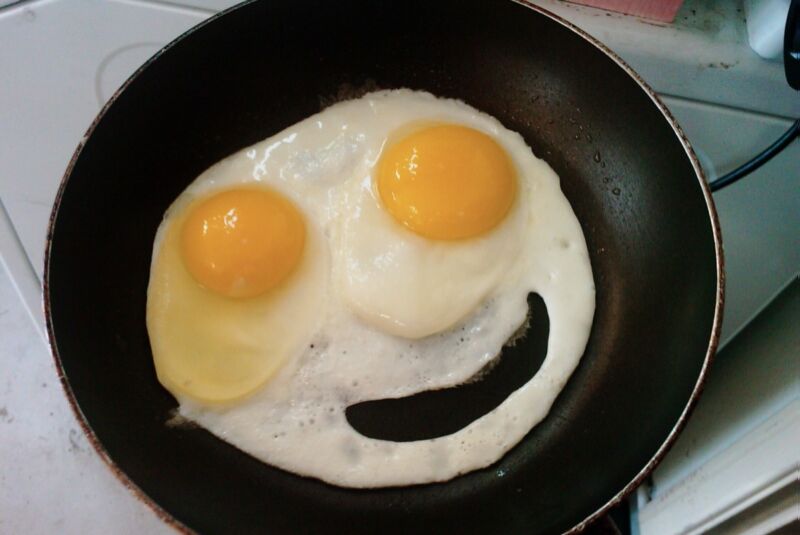 Eggs fried in a pan are arranged in such a way that they look like a smiling face.
