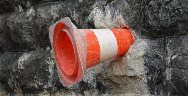 An orange traffic cone has been inserted into a stone wall.