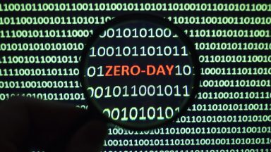 The phrase Zero Day can be spotted on a monochrome computer screen clogged with ones and zeros.