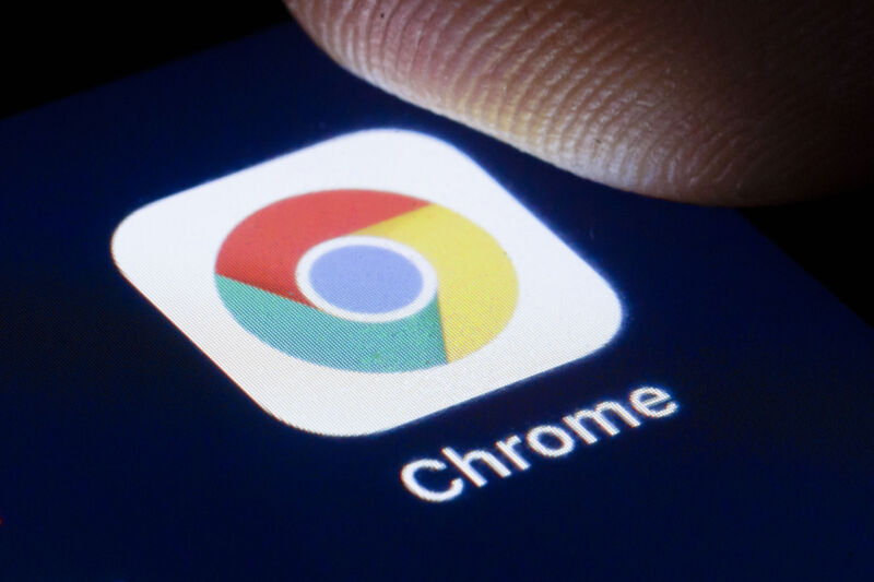 Extreme close-up photograph of finger on Chrome icon on smartphone.