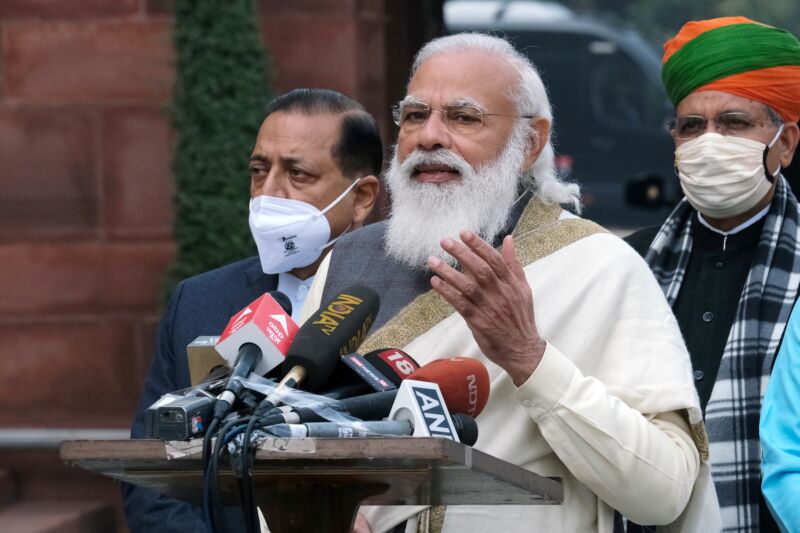 A Man With A Long White Beard Speaks Into A Microphone.