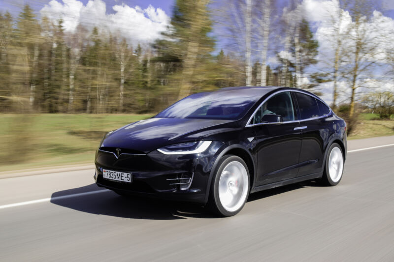 Trees Blur Behind A Sleek Black Crossover As It Speeds Down A Highway.