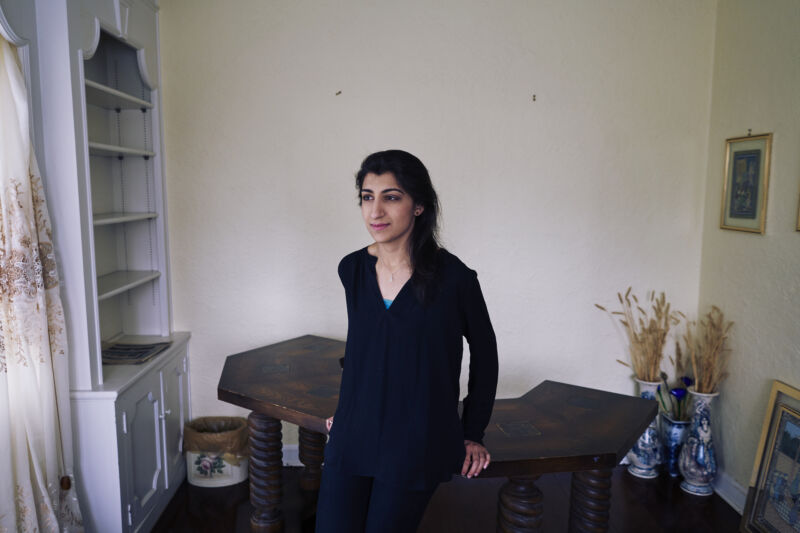 A young woman poses for a photo in a spartan apartment.