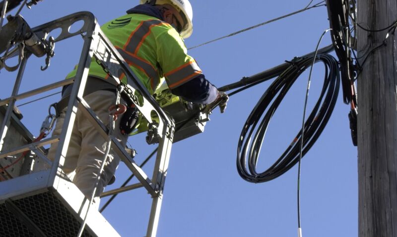 AT&T technician working with cables on a utility pole.