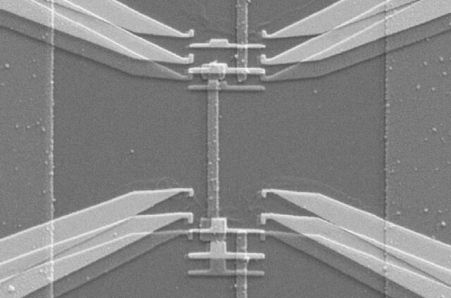 Scanning electron micrograph shows the device used to implement the gambling demon. The tapered structures on each side are electrodes from which single electrons can jump onto the strip-shaped copper island in between. Each jump is like a gas molecule passing through the demon’s shutter. 