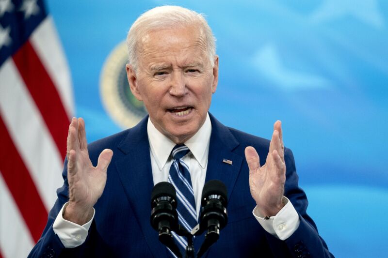 President Joe Biden speaking into a microphone and gesturing with his hands.