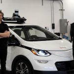 Promotional image of two men standing next to an electric car.