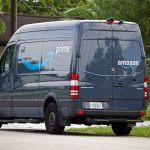 A dark blue van with multiple Amazon logos.