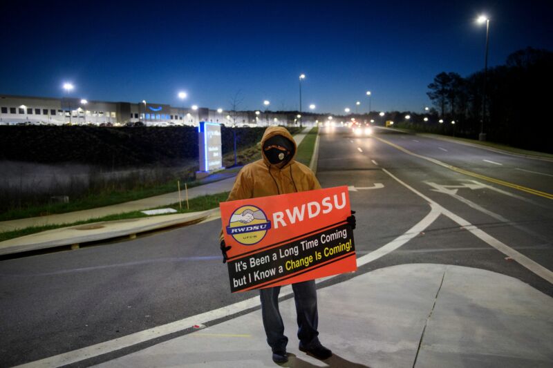 A Union Supporter Stands Before Sunrise Outside The Amazon Fulfillment Center On March 29, 2021 In Bessemer, Alabama.