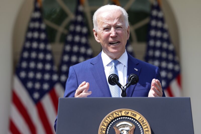 Technology President Joe Biden speaking at a podium, with American flags in the background.
