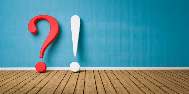 Illustration of a question mark and exclamation point on a wooden floor, leaning against a wall.