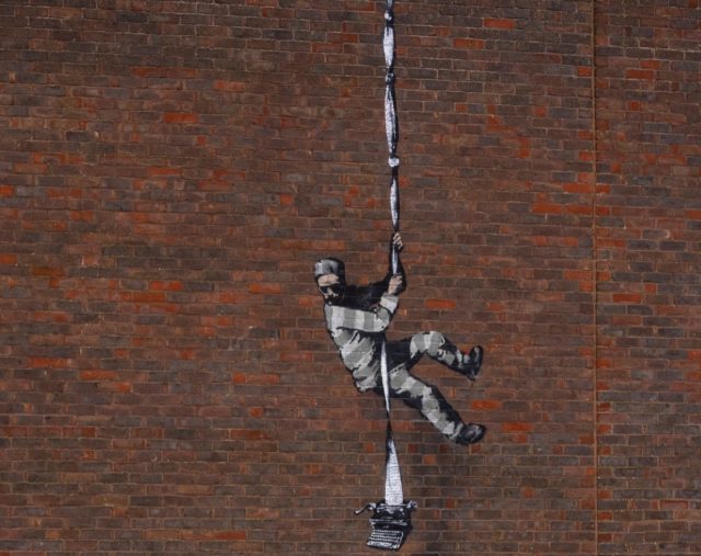 Art work by graffiti artist Banksy, depicting a prisoner escaping with a typewriter—a tribute to one of its famous former prisoners, Oscar Wilde—in Reading, England.