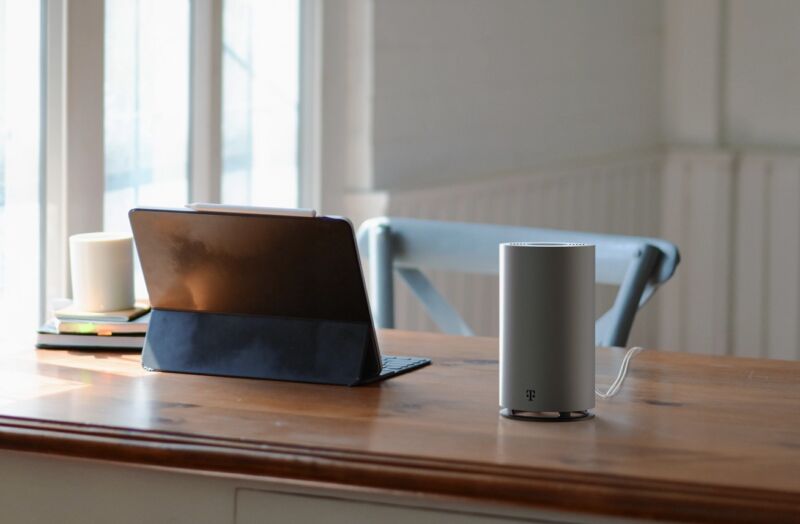 T-Mobile's 5G home Internet gateway sitting on a desk next to a tablet.