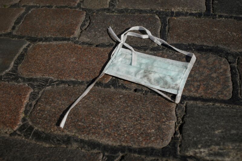 A thrown-away surgical mask lays on the ground.