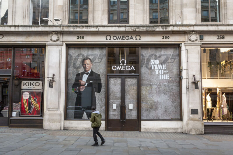 A man walks past a promotion for the James Bond fIlm <em>No Time to Die</em> at the closed Omega store in London on March 27, 2020.