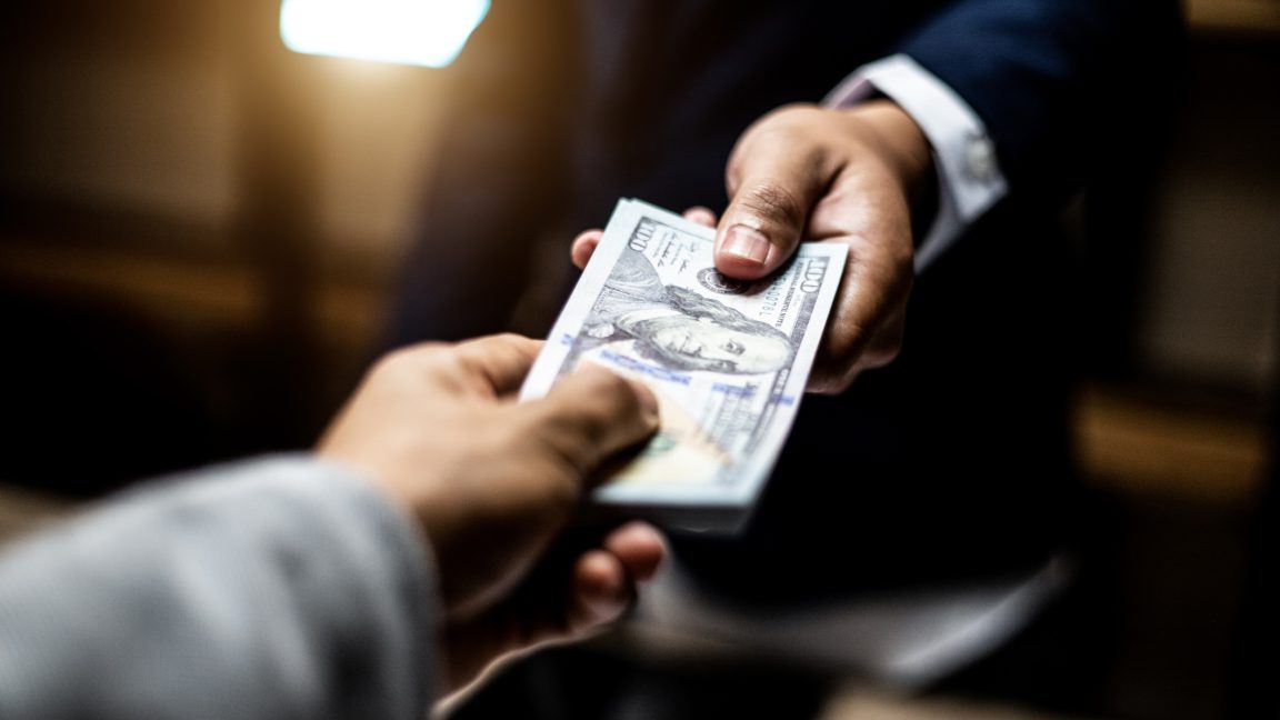 A judge's gavel resting on a pile of one-dollar bills