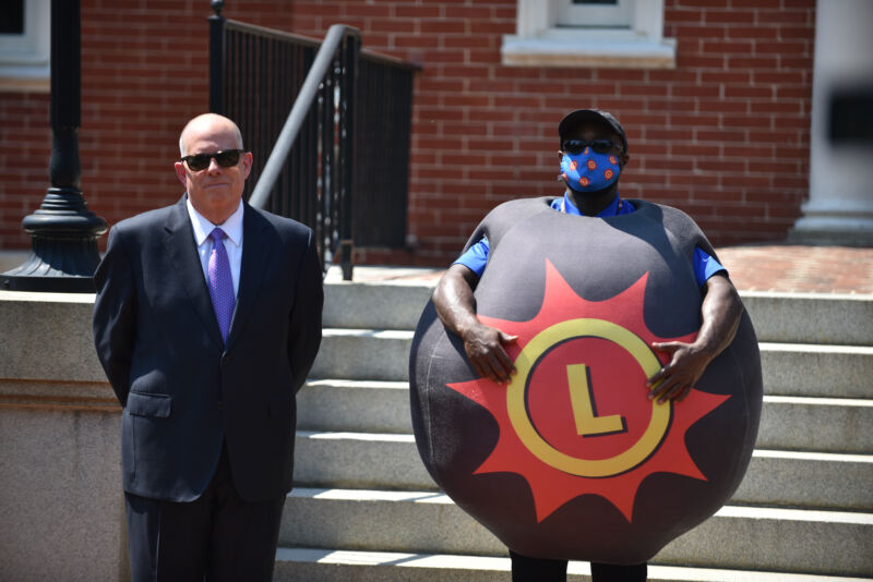 Maryland Governor Larry Hogan stands next to a person dressed as a lottery ball during a press conference on May 20 announcing the state's VaxCash promotion.