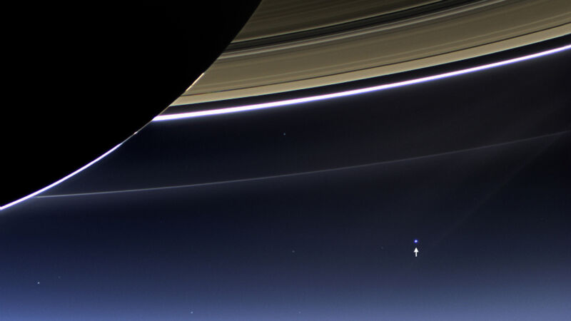 Image of the Earth as a small dot below Saturn's rings.