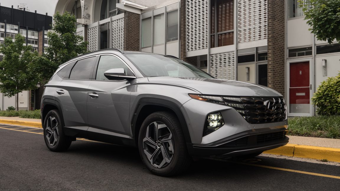 A silver Hyundai Tucson Hybrid parked outside a row of midcentury townhouses