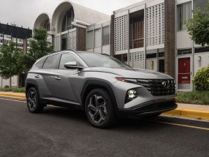 A silver Hyundai Tucson Hybrid parked outside a row of midcentury townhouses