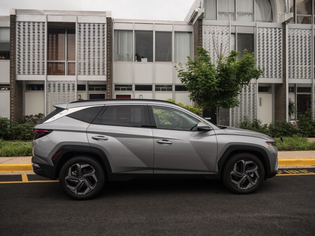 A silver Hyundai Tucson Hybrid parked outside a row of midcentury townhouses