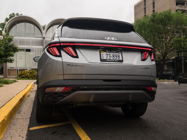 A silver Hyundai Tucson Hybrid parked outside a row of midcentury townhouses