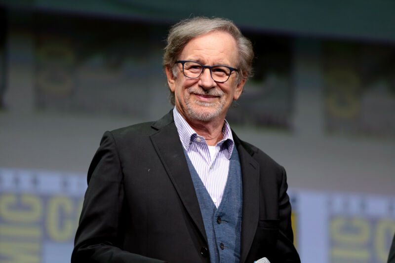 A smiling older man in a open-collared suit.