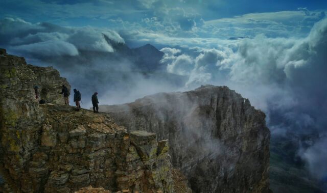 Glacier National Park, MT, USA - August 17, 2016: Climbers on the northwest ridge of Chief Mountain admire the view above the clouds after a passing summer storm.