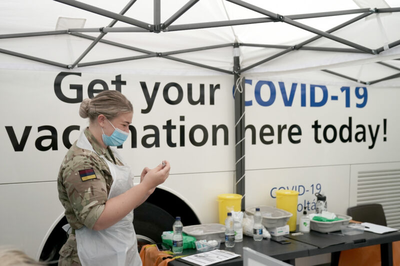 A serious woman in military fatigues prepares an injection.