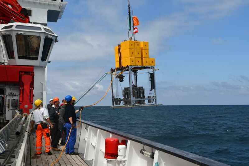 Image of people on a boat about to lower equipment into the ocean.